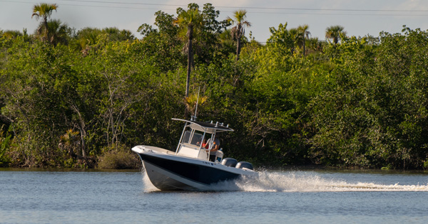 Motorboat traveling through a calm waterway border by green mangroves