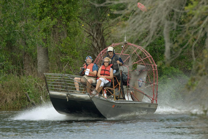People riding an airboat on a lake.