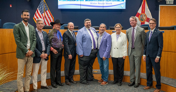 SFWMD Governing Board Members standing in a council chamber with flags behind them